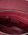 Close-up of the interior of a burgundy leather bag, showing a zippered pocket with a small leather brand label that reads 'RICO RINALDI'.