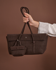 Woman holding Rico Rinaldi Mendy Dark Coffee shoulder bag, premium East-West handbag for work, travel and everyday use