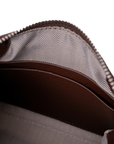 Close-up of the interior of a brown leather zippered pouch or wallet, showing a gray and white herringbone patterned lining. 2 pocket slot inside pouch. Coin pouch or card. Rico Rinaldi Malaysia.