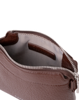 Close-up of a brown textured leather pouch with a silver zipper, showing the interior lining and a small interior label, on a white background. Rico Rinaldi Norri Women's Convertible Shoulder and Crossbody Bag with Detachable Pouch.