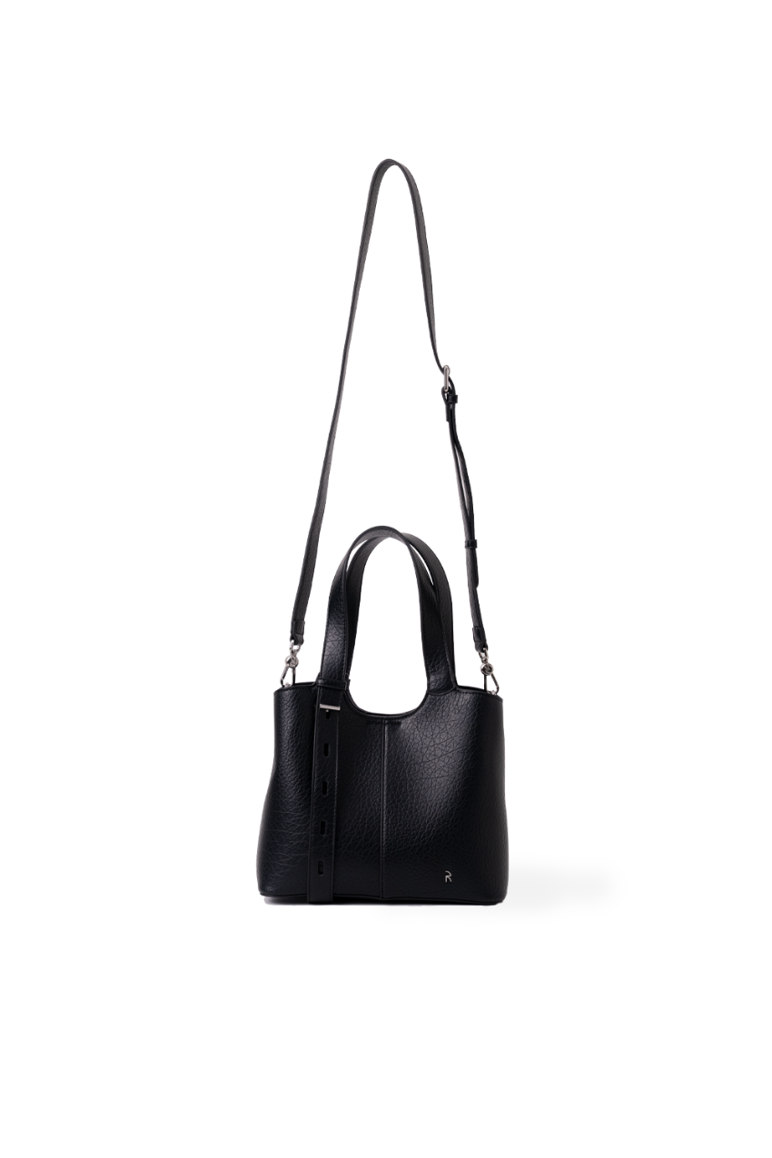 A black leather handbag with a top handle, a long shoulder strap, and a small hanging tassel, shown against a plain white background. Silver hardware.
