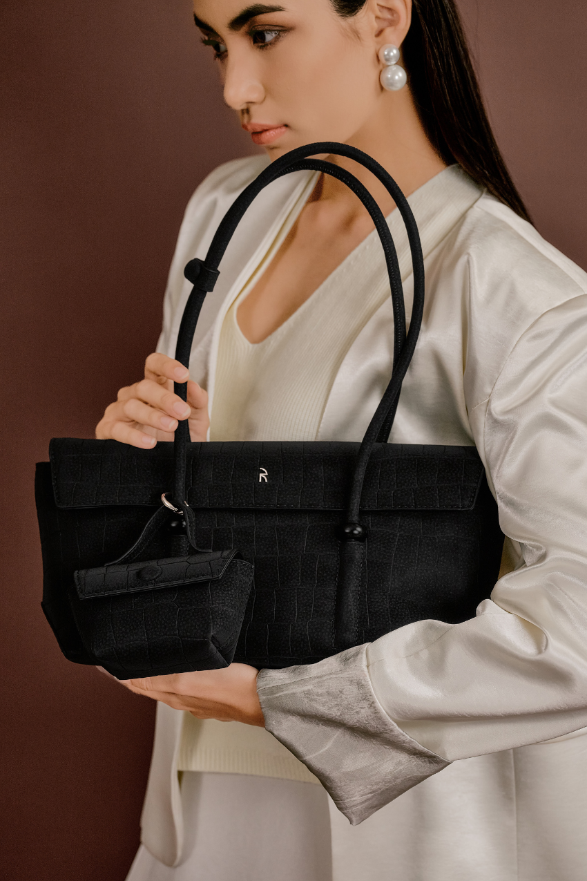 Model wearing Rico Rinaldi Mendy Black East-West shoulder bag, minimalist crocodile embossed vegan leather office handbag for women