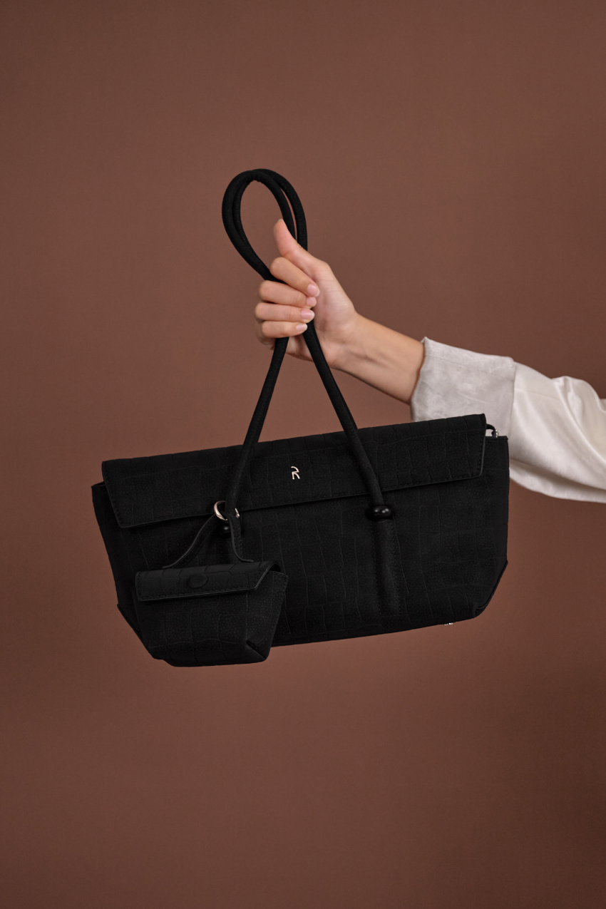 Woman carrying Rico Rinaldi Mendy Black shoulder bag with detachable mini pouch, premium East-West work handbag in crocodile embossed vegan leather