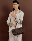 Model wearing Rico Rinaldi Mendy Dark Coffee shoulder bag, elegant East-West women's handbag for work, office and everyday wear