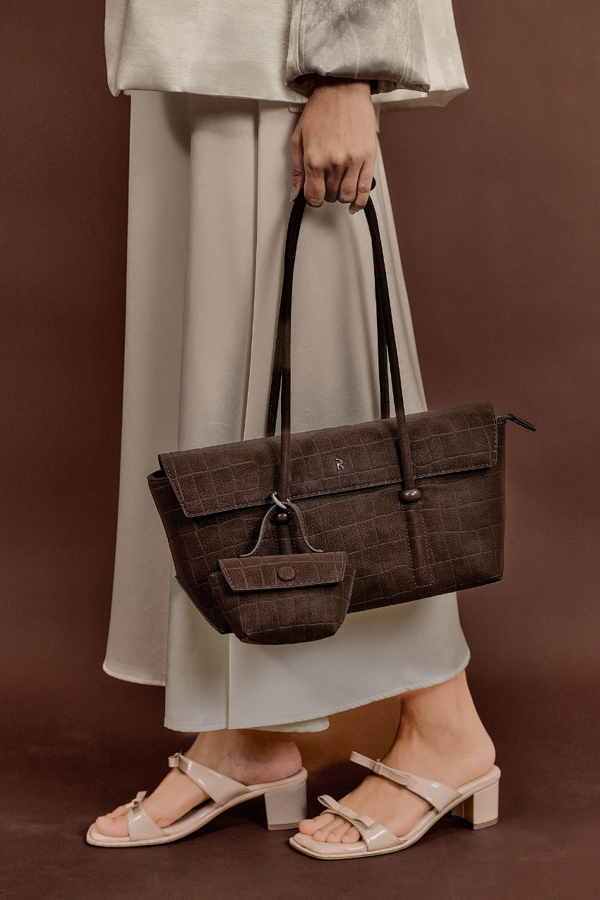 Model carrying Rico Rinaldi Mendy Dark Coffee East-West shoulder bag, premium crocodile embossed PU vegan leather women's work handbag with detachable mini pouch
