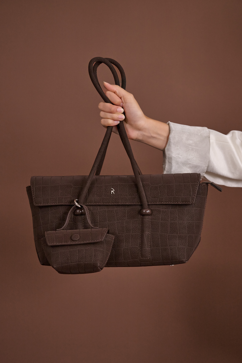 Woman holding Rico Rinaldi Mendy Dark Coffee shoulder bag, premium East-West handbag for work, travel and everyday use