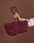 Woman holding Rico Rinaldi Mendy Deep Maroon shoulder bag, elegant East-West handbag for work, travel and everyday wear
