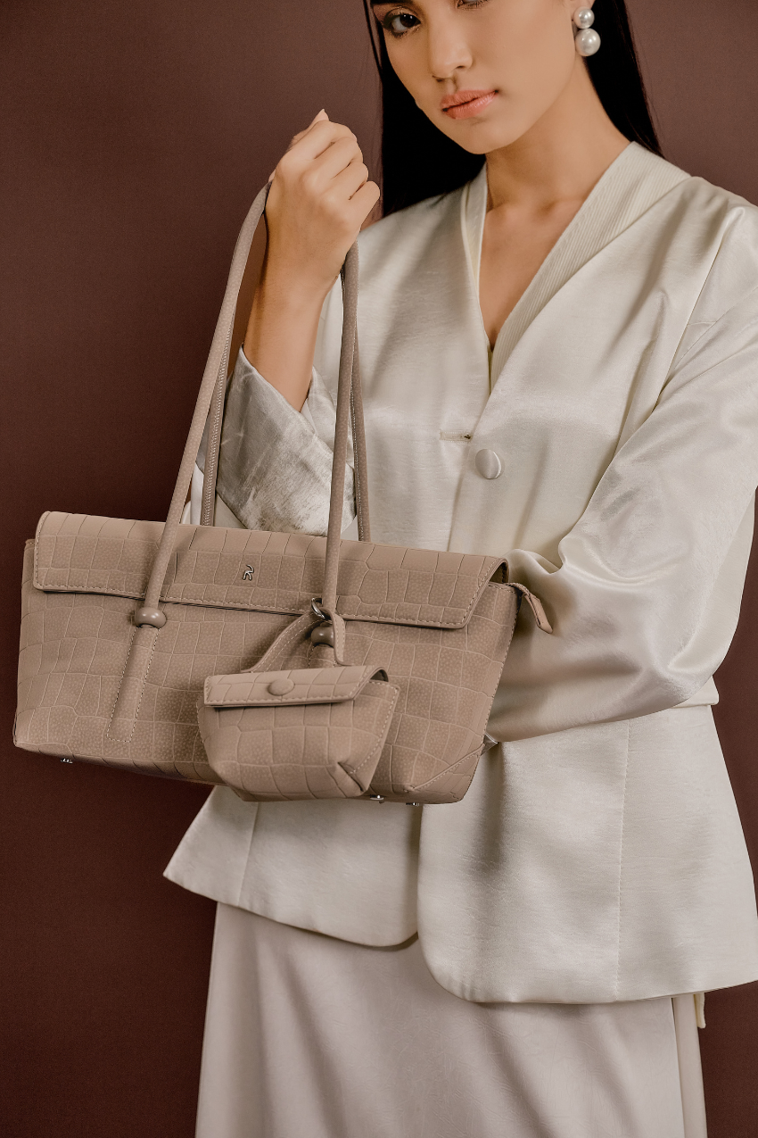 Model wearing Rico Rinaldi Mendy Latte shoulder bag, minimalist East-West women's handbag for office, commuting and daily use