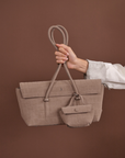 Woman holding Rico Rinaldi Mendy Latte shoulder bag, elegant East-West handbag for work, travel and everyday wear